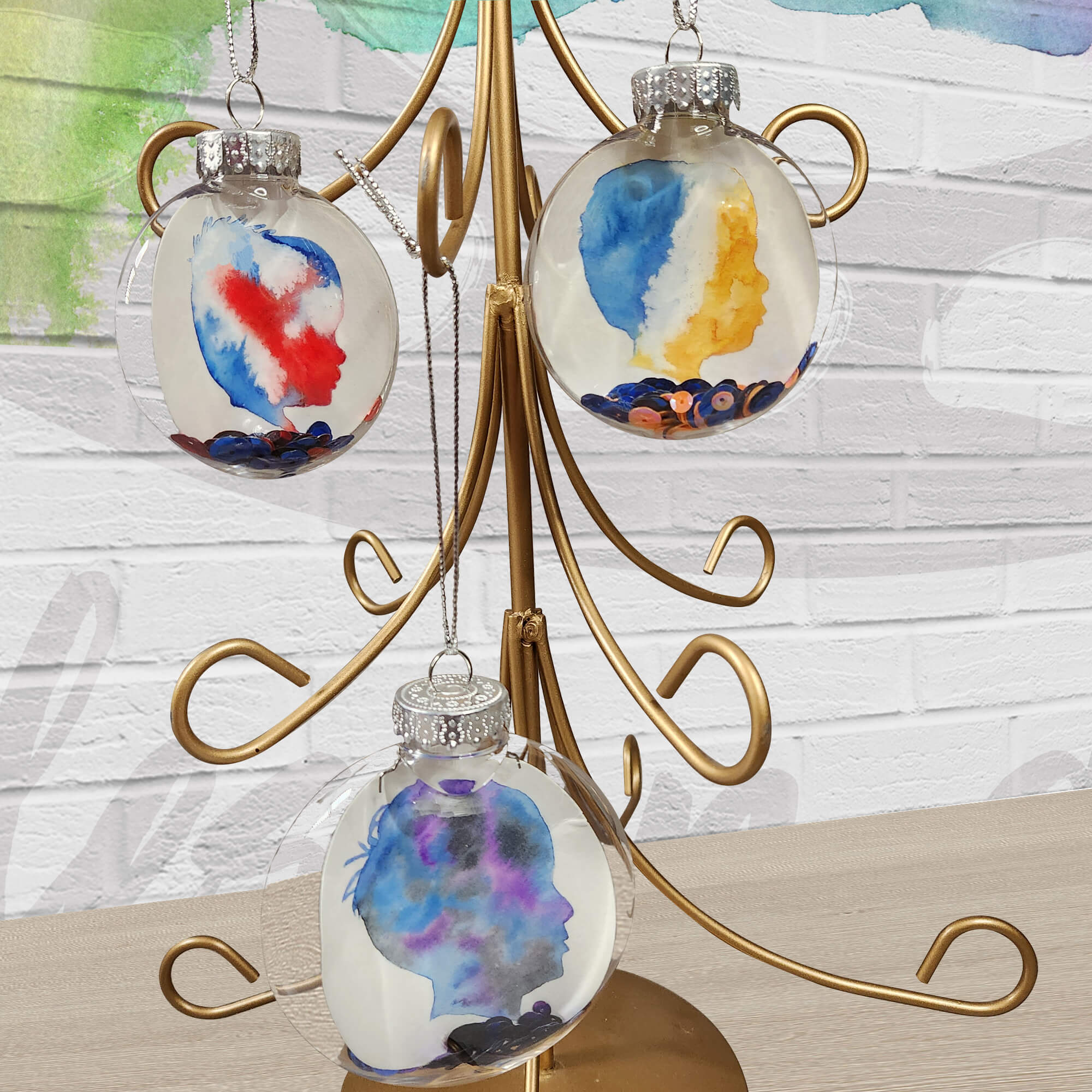 Ornament Tree featuring three silhouette ornaments on a wood table with white brick background